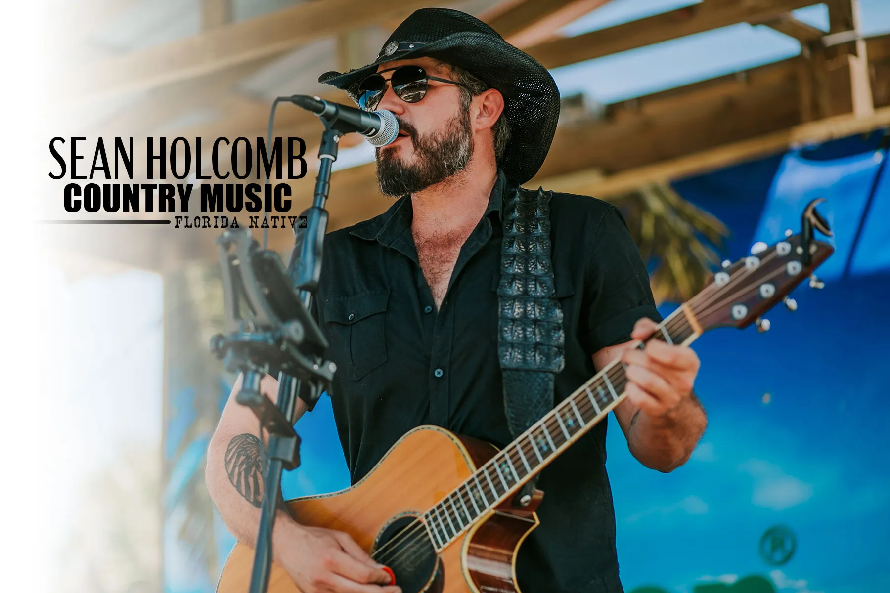 Sean Holcomb singing into a microphone and playing acoustic guitar